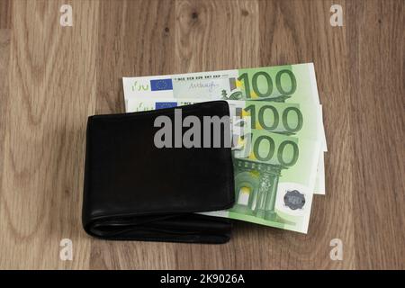 300 euros sticking out of the wallet. Three paper banknotes of 100 euros each. Symbol for growing expenses, inflation, paying household bills, salary. Stock Photo