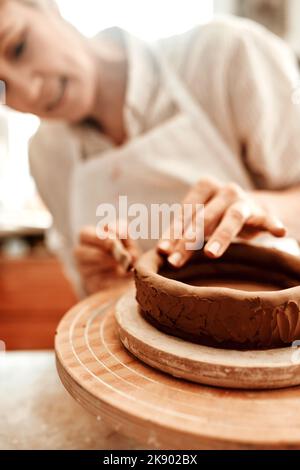 I started working with clay from a young age. a woman shaping a clay pot in her workshop. Stock Photo