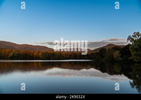 A large lake reflecting mountains covered with dense forest in the evening Stock Photo