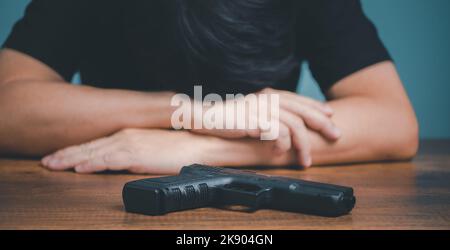 Sad and depressed Businessman with gun on the desk. Stock Photo