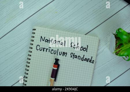 Concept of National School Curriculum Standards write on a book isolated on Wooden Table. Stock Photo