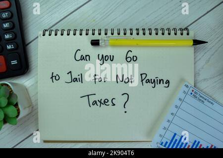 Concept of Can You Go To Jail For Not Paying Taxes? write on a book isolated on Wooden Table. Stock Photo
