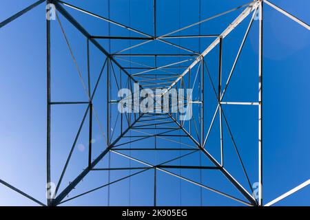 An abstract image looking straight up a transmission tower or pylon carrying 132kv electricity cables against a clear blue sky. Stock Photo