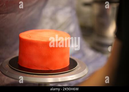 cook preparing a red frosted cake using air bush Stock Photo