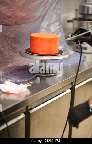 cook preparing a red frosted cake using air bush Stock Photo