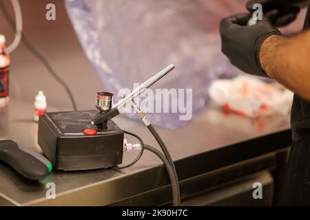 cook preparing a red frosted cake using air bush Stock Photo