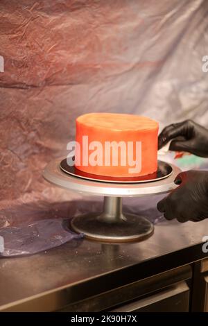 cook preparing a red frosted cake using air bush Stock Photo