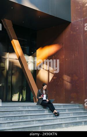 Portrait of successful businesswoman working outside on fresh air, sitting with during remote work on warm summer day. People person outdoor. Escaped Stock Photo