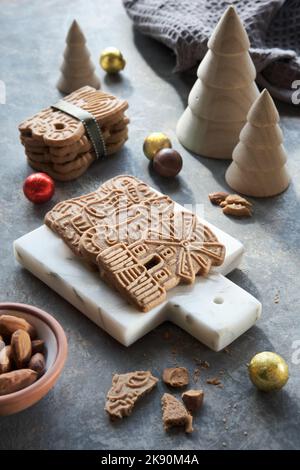Speculoos or Spekulatius, Christmas biscuits, chocolate balls and almonds on a table with wooden Xmas tree toys. Traditional German sweets, cookies Stock Photo