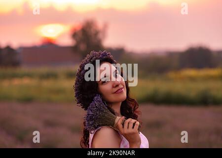A girl in the lavender field on the sunset with bouquet of lavender Stock Photo