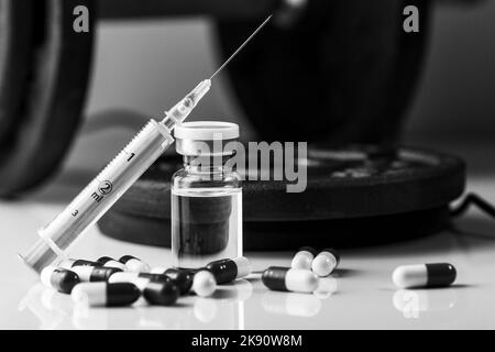 A black and white pharmaceutical syringe with needle and medical pills - illegal doping drugs in sport Stock Photo
