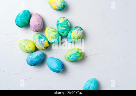 Group of vibrant hand-painted marbled Easter eggs scattered naturally on a light background, overhead view Stock Photo