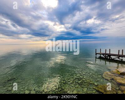 A scenic view of Lake Huron and wooden dock on a cloudy day at Mackinac Island, Michigan Stock Photo
