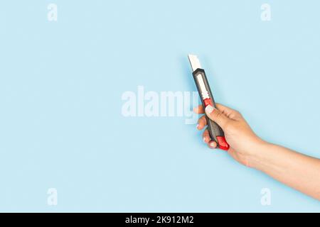 Woman hand holding a black cutter on a light blue background with copy space Stock Photo