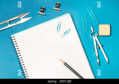 Open blank notebooķ and student utensils on a blue background Stock Photo