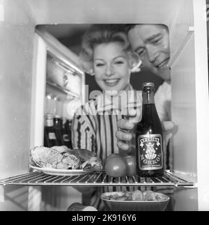 In the kitchen 1950s. A couple in their kitchen and at the refrigerator where the food and beer is kept.  Sweden 1959. Kristoffersson ref CH73-1 Stock Photo