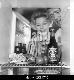 In the kitchen 1950s. A couple in their kitchen and at the refrigerator where the food and beer is kept.  Sweden 1959. Kristoffersson ref CH73-6 Stock Photo