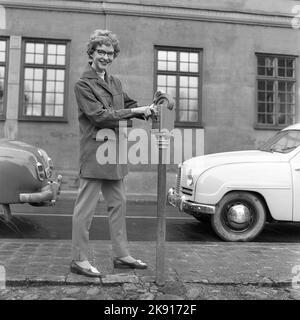 In the 1950s. A woman is pictured in the street and at a parking meter. A device used to pay for parking. When having put in a coin, you turned the lever and an arrow inside the meter showed for how long you had paid for parking. Sweden 1959 Kristoffersson ref CF59-5 Stock Photo