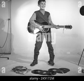 Boy in the 1950s. A boy is photographed in a studio and plays the guitar, perhaps with the Rock n' roll artists of the time in mind. Sweden 1959 Kristoffersson ref CF62 Stock Photo