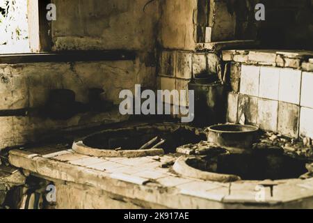 An old ruined room with worn tiles and dirty and blackened walls Stock Photo