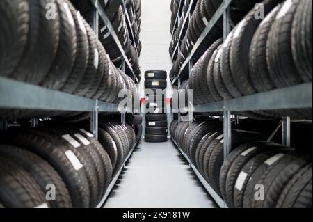 Perspective row of stack shelves with arranged new tires in store room of car service Stock Photo