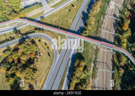 Footbridge with cycle path and pedestrian walkway over a city highway and railway in Krakow, Poland. Aerial view from above Stock Photo