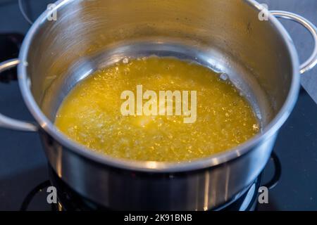 Melting butter in a stainless steel saucepan on the black stove, cooking concept, selected focus Stock Photo