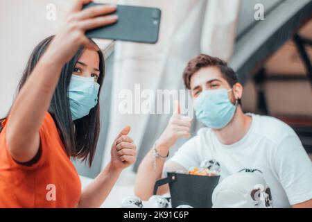 Two friends boy and girl taking a selfie in medical masks while making Halloween skull gang decorations Stock Photo