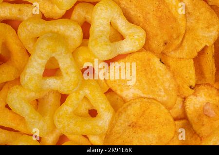 Crispy potato and corn chips, close-up view from above. Stock Photo