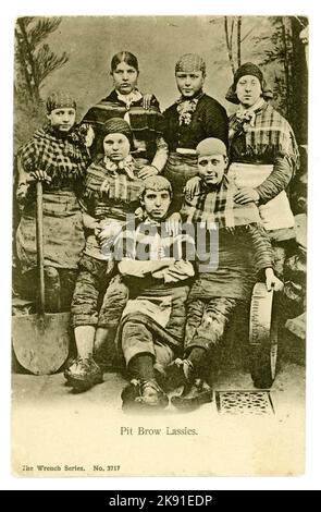 Original postcard of Pit Brow 'Lassies' from the Victorian era, wearing working clothes, including trousers with tools of the trade -  shovels and sieves, working  tools. Wigan, Lancashire, U.K.  posted February 1906 but photographed circa 1900. Stock Photo