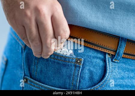 a pack of white pills sticking out from front pocket of jeans - close-up with selective focus Stock Photo