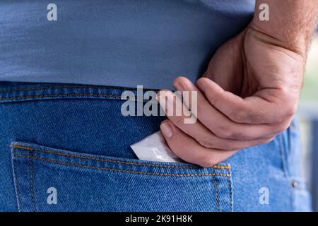 man's hand pulling a packet of drugs out of the back pocket of a pair of jeans Stock Photo