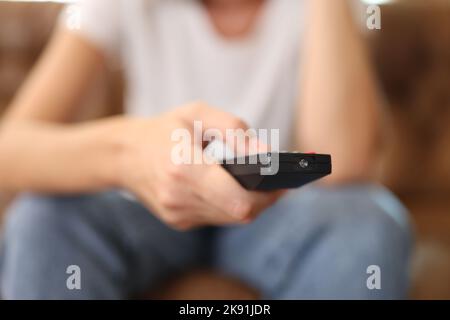 Female hand holding tv remote control and surfing programs on television Stock Photo
