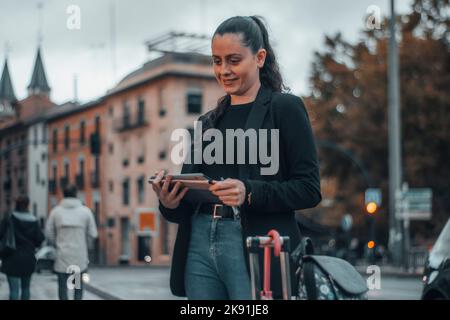 An attractive caucasian woman in a formal style with a tablet in her hands in the street. Stock Photo
