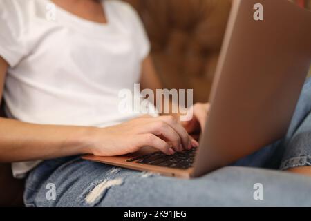 Woman typing on modern laptop with sticker on cover Stock Photo