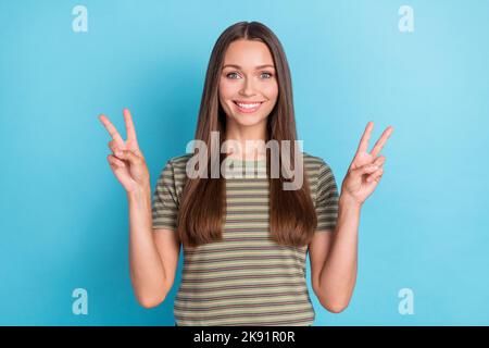 Photo of gorgeous satisfied optimistic girl with straight hairdo dressed striped t-shirt showing v-sign isolated on blue color background Stock Photo