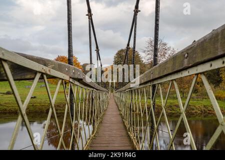Looking along the Hebden Suspension Bridge which spans the River Wharfe in the Yorkshire Dales, seen in October 2022. Stock Photo