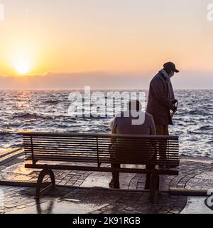 man sitting alone on a bench in front of the lake Stock Photo