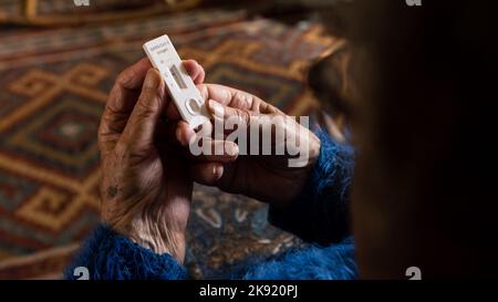 Caucasian grandma makes a rapid home test device for Covid19 virus with a negative result. Grandmother using an antigen cassette of pcr express test f Stock Photo