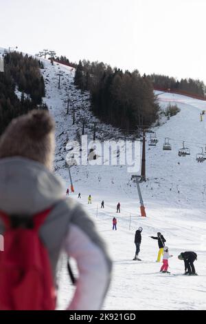 a woman from the back looking at people in the snow Stock Photo