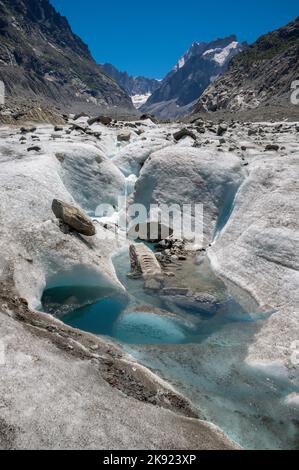 The glacial stream on the glacier Mer de Glace with the Garand Jorasses in the background. Stock Photo