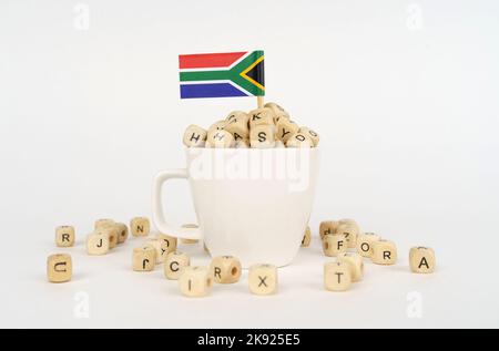 The flag of South Africa sticks out of a cup with cubes on which letters are depicted. Symbol of education. Stock Photo