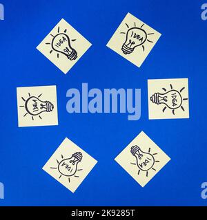 Light bulbs drawn on sticky notes placed in a circle with empty space for text or logo. Hand drawn doodle lineart. Ideas, inspiration and creative thi Stock Photo