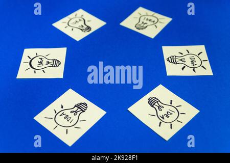 Light bulbs drawn on sticky notes placed in a circle with empty space for text or logo. Hand drawn doodle lineart. Ideas, inspiration and creative thi Stock Photo
