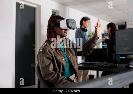 Software developer wearing with vr heaset to create programming server with html script on terminal window. System engineer using virtual reality glasses to plan new interface. Stock Photo