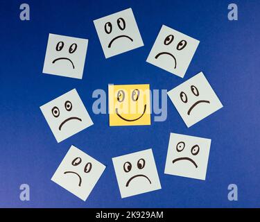 Sticky notes with hand drawn Smiley face and Sad faces on blue background. Positive way of thinking concept. Positive overcomes negative Stock Photo