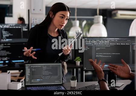 Diverse team of app developers using computer to write html code and develop algorithm program in software company office. Programmer working on user interface with html script and terminal window. Stock Photo