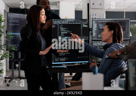 Diverse team of programmers coding html script information on computer at desk table, parsing source code in software agency. Web developers compiling app language innovating online server algorithms. Stock Photo