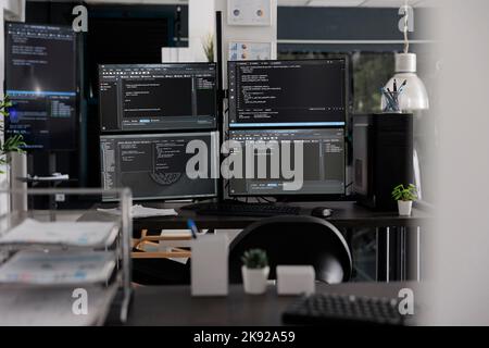 Empty it office with computer screens on desk, computers in background running programming code and algorithms on terminal window. Firewall network servers in software company. Stock Photo