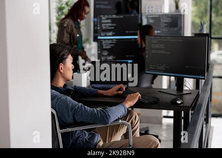 Asian disabled software developerr typing programming language on computer, using big data and firewall server. System engineer with physical impairment in disability friendly it agency. Stock Photo